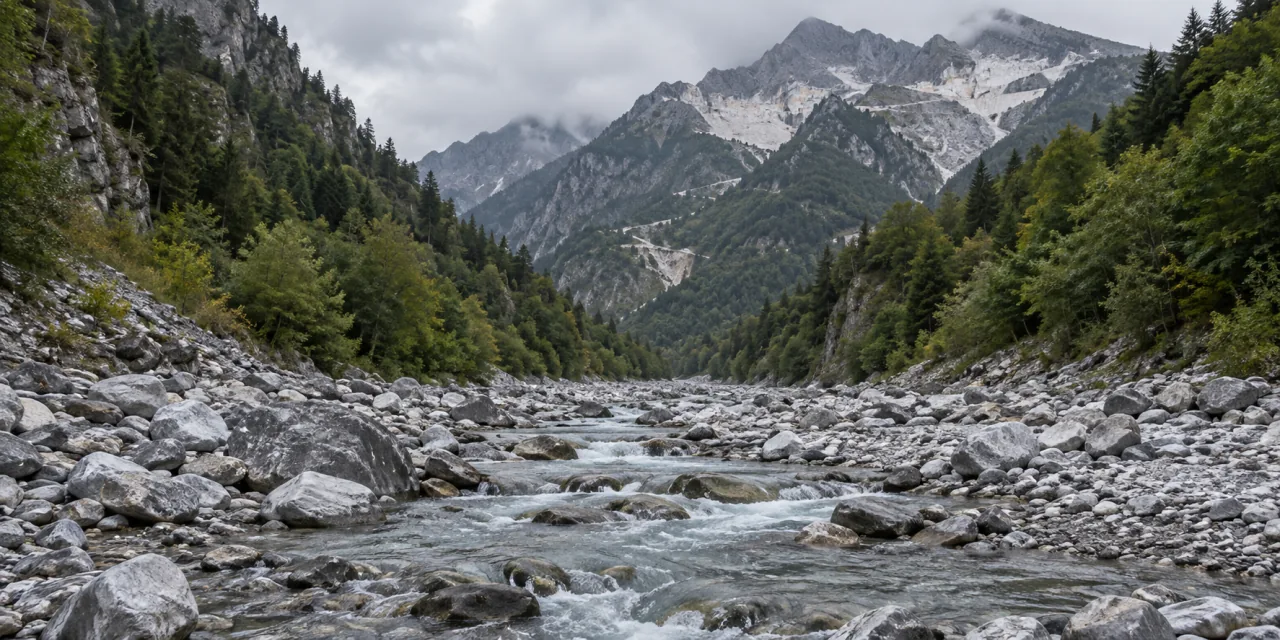 Letto di un torrente di montagna tra versanti boscosi, con le cave di marmo sulle cime